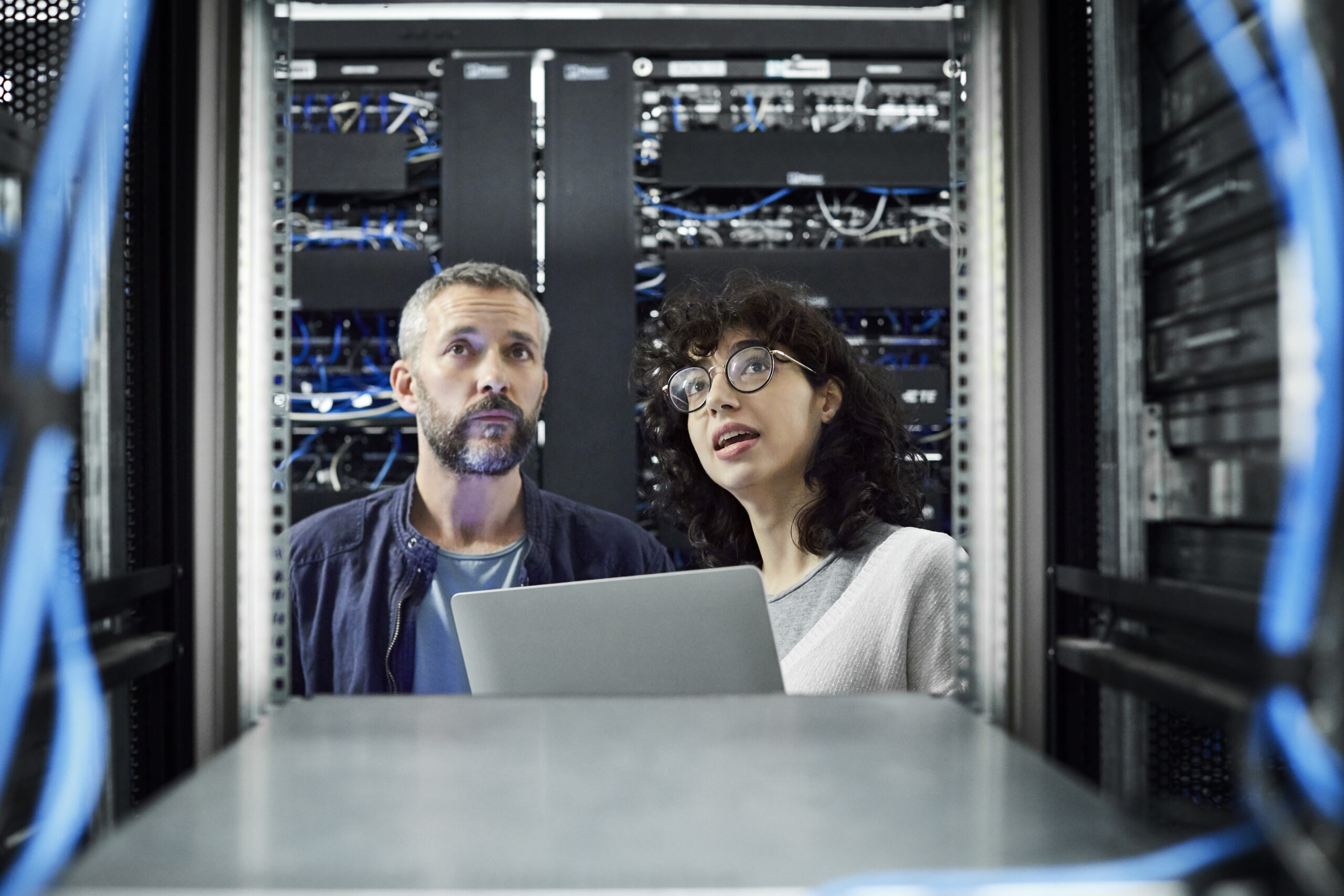 Female technician discussing with male coworker in server room
